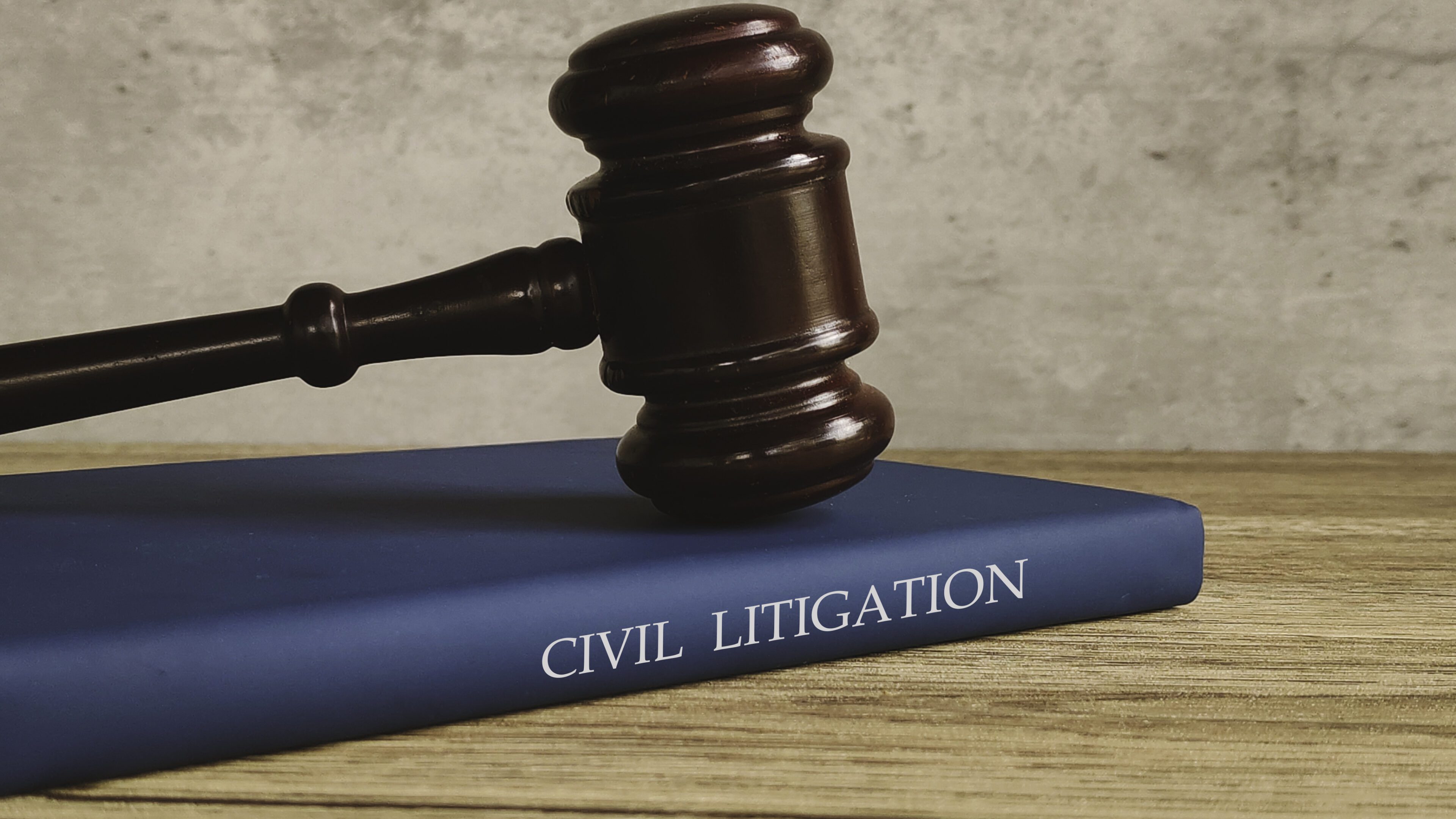 Gavel and a book titled CIVIL LITIGATION on a wooden table, symbolizing justice and the legal process.